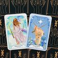 Taro kortos, dvi atverstos kortos (Three of Wands ir Two of Wands) su pastelinėmis iliustracijomis ir juodomis nugarėlėmis su auksiniais simboliais, artimas kampas