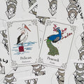 Kortos: spalvotos gyvūnų oracle kortos, pelikanas (Patience) ir povas (Pride) – arti išdėstytos ant baltos fono