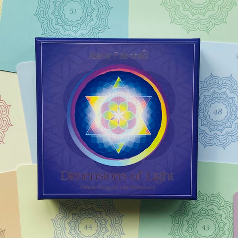 Kortų rinkinys Dimensions of Light violetinėje dėžutėje su spalvota mandala centre, padėtas ant pastelinio numeruoto fono