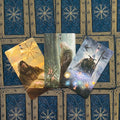 tarot kortos – trys atverstos kortos su senovinių burtininkų iliustracijomis ir spalvotomis švytinčiomis orbomis ant mėlyno auksinio fono