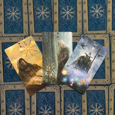 tarot kortos – trys atverstos kortos su senovinių burtininkų iliustracijomis ir spalvotomis švytinčiomis orbomis ant mėlyno auksinio fono