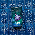 Tarot kortos Triple Goddess dėžutė žalia–violetinė, 78 kortų komplektas, dėžutė centre ant mėlynos nugarėlės raštuoto kortų išdėstymo