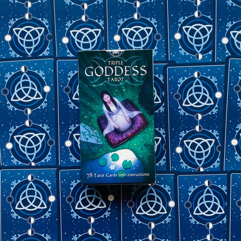 Tarot kortos Triple Goddess dėžutė žalia–violetinė, 78 kortų komplektas, dėžutė centre ant mėlynos nugarėlės raštuoto kortų išdėstymo