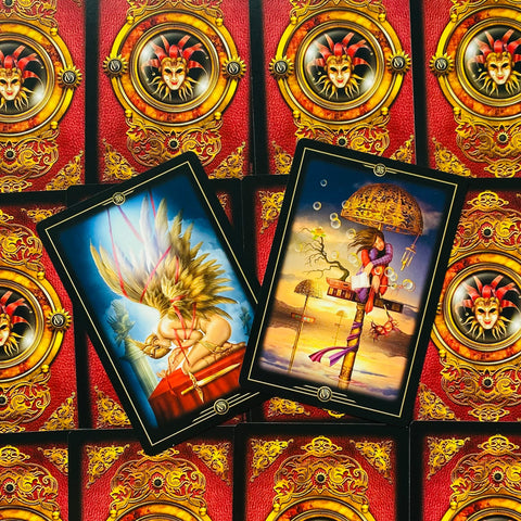 Tarot kortos atverstos dviem kortom su ryškiomis iliustracijomis ant raudonai auksinių nugarėlių, pabrėžiant meno detales
