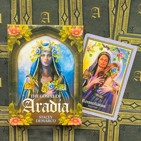 Orakulo kortų rinkinys The Gospel of Aradia, mėlyno ir aukso dėklo viršelis šone atversta „Reconciliation“ korta