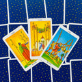 tarot kortos Rider–Waite: trys lazdų kortos išdėstytos fanu, geltoni piešiniai ir mėlynos nugarėlės su auksinėmis žvaigždėmis