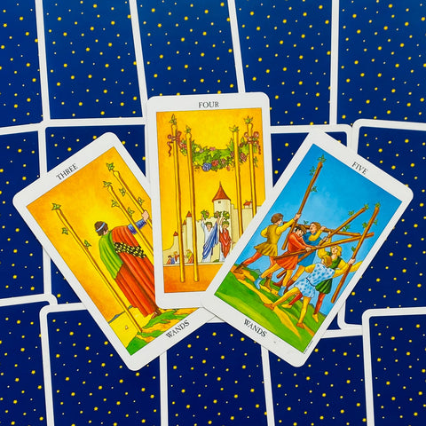 tarot kortos Rider–Waite: trys lazdų kortos išdėstytos fanu, geltoni piešiniai ir mėlynos nugarėlės su auksinėmis žvaigždėmis