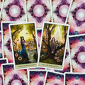 Tarot kortos devyni ir dešimt pentaklių su spalvingomis iliustracijomis ir rožinėmis nugarėlėmis, parodyta iš viršaus