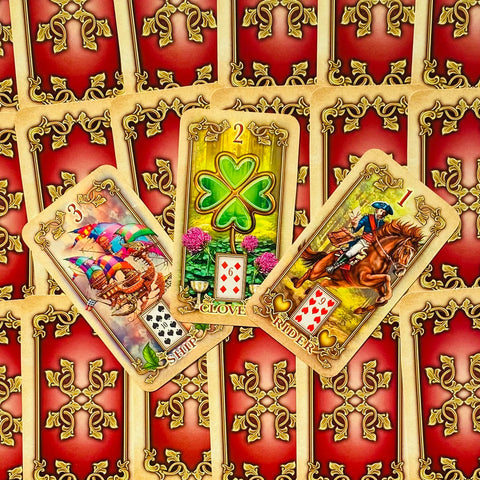 Lenormand kortos su atvertomis Laivas, Dobilas ir Raitelis kortomis ant raudonai auksinio ornamentuoto nugarėlių fono