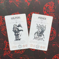 tarot kortos Halphas ir Phenex — baltos kortos su juodomis iliustracijomis ant raudono simbolių fono, atverstos kampu