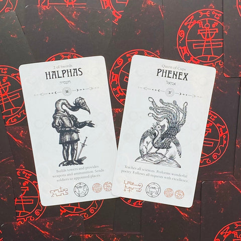 tarot kortos Halphas ir Phenex — baltos kortos su juodomis iliustracijomis ant raudono simbolių fono, atverstos kampu