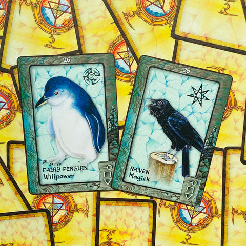 oracle kortos su gyvūnų motyvais — artimas dviejų kortų rinkinys: mėlynas pasakų pingvinas (Willpower) ir juodas varnas (Magick) ant geltono ornamentuoto fono