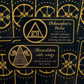 Orakulų kortos juodos su auksinėmis detalėmis, artimas priekinis kadras, rodantis Philosopher's Stone ir Abracadabra dizainus