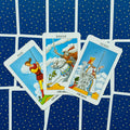 Tarot kortos Rider–Waite Swords komplektas: trys atverstos kortos (Page, Knight, Queen) ant mėlyno žvaigždėto nugarėlio