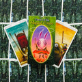Tarot kortos "Magical Forest" žalios dėžutės priekyje su trimis išskleistomis iliustruotomis kortomis