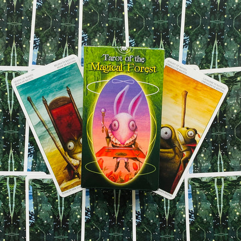 Tarot kortos "Magical Forest" žalios dėžutės priekyje su trimis išskleistomis iliustruotomis kortomis