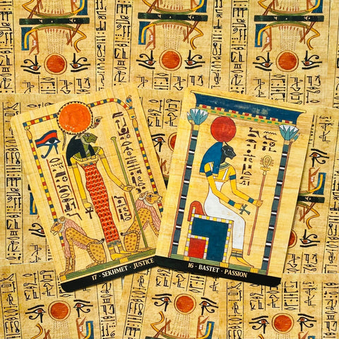 Tarot kortos, Egipto dievybių Sekhmet (17) ir Bastet (16) ant papiruso fono, dvi kortos persidengiančios, priekinis pasviręs žvilgsnis