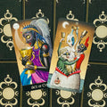 Tarot kortos, dvi kupų kortos (Ace ir Three of Cups) parodytos iš priekinio plano ant juodo ornamentuoto dėklo