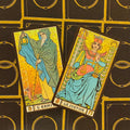 Tarot kortos Rider–Waite stiliaus su auksiniu blizgiu fonu, dvi kortos (Ermitas ir Teisingumas) padrikai padėtos iš viršaus
