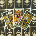Tarot kortos trijų kortų išdėstymas: V, VI ir VII lazdelės atidengtos centre ant juodos auksinės nugarėlės