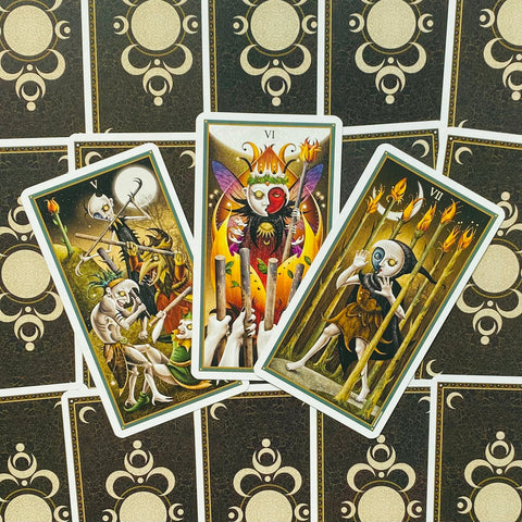 Tarot kortos trijų kortų išdėstymas: V, VI ir VII lazdelės atidengtos centre ant juodos auksinės nugarėlės