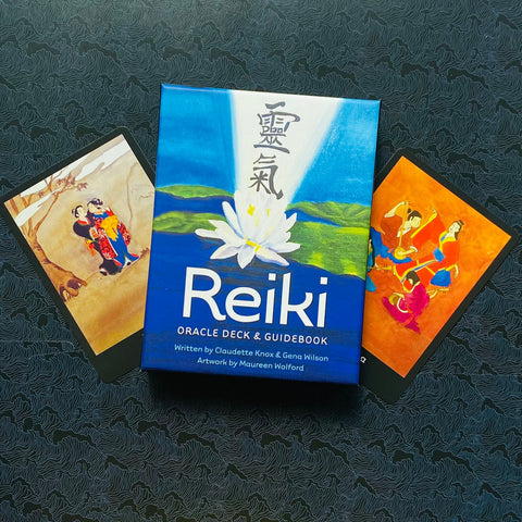 Reiki kortų kaladė mėlyname dėkle su baltu lotosu centre, pateikta kartu su dviem spalvingomis kortomis šonuose
