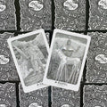 Tarot kortos, dvi atverstos kortos su baltomis kraštinėmis (Muspell ir Suld) ant juodai baltų nugarėlių fono