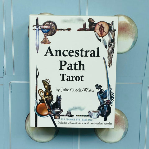 Taro kortų rinkinys Ancestral Path (autorė Julie Cuccia‑Watts), baltas priekinis dėklas ant mėlyno fono, komplektą sudaro 78 kortos