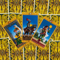 Tarot kortos su auksine nugarėle, trys ryškios kortos fanuotos kampu su mėlynomis scenomis, skirtos parduotuvės aprašymui
