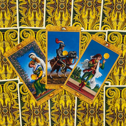 Tarot kortos su auksine nugarėle, trys ryškios kortos fanuotos kampu su mėlynomis scenomis, skirtos parduotuvės aprašymui