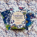 Orakulo kortos The Language of Flowers komplektas su gėlių motyvais dekoruota dėžute ir keliomis atverstomis iliustruotomis kortomis
