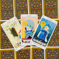 tarot kortos Pentacles komplektas su ornamentinėmis tamsiai geltonomis nugarėlėmis, trys atverstos kortos (karalius, karalienė, tūzas) fanuotai išdėstytos viršuje