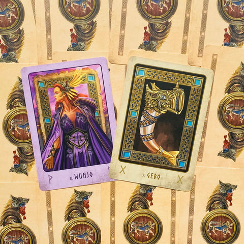 Tarot kortos su ilustruotomis runomis: violetinė Wunjo figūra ir auksinė Gebo ragas, artimas detalus atvaizdas parduotuvės galerijoje