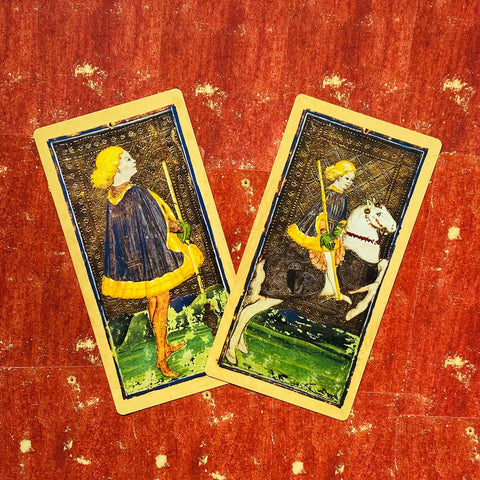 Tarot kortos Marseille stiliaus – dviejų Lazdų kortų artimas kadras su geltonais akcentais ant nusidėvėjusio raudono fono, unikalus variantas