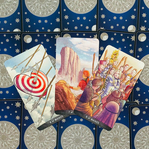 tarot kortos atvertos: trys priekinės kortos (8, 7 ir 6 lazdelės) ant mėlyno žvaigždėto nugarėlių, matomos iš viršaus