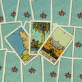 Tarot kortos Rider stiliaus — trijų kortų išdėstymas ant turkio mėlyno gėlių nugarėlių, akcentuojantis namų ir pokyčių temą