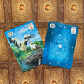 Lenormand kortos su baltų gervių iliustracija ir mėlynu žvaigždėtu nugarėliu, dvi kortos kampuotos ant ornate rudos fono, rodoma priekis ir nugarėlė variantas
