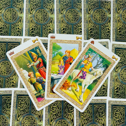 tarot kortos trijų kortų išdėstymas su spalvotomis vidinėmis iliustracijomis ir žalios ornamentuotos nugarėlės