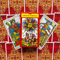 Tarot kortos Marseille komplektas, raudona dėžutė centre ir dvi atvertos kortos ant ornamentinio raudono fono