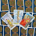 Tarot kortos Rider–Waite stiliaus rinkinys, trys atvertos kortos (Lazda, Dvi Lazdos, Pentaklis) ant mėlynos nugarėlės rašto