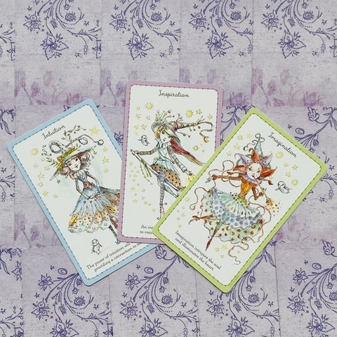 orakulo kortos, trijų kortų komplektas su pastelėmis rėmeliais (mėlyna, rožinė, žalia) ant violetinio raštuoto fono, priekiai aiškiai matomi