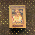 Tarot kortos Touchstone (Kat Black) – rožinė auksinė dėžė, matomas dėžės priekis su renesansine iliustracija ir autoriaus vardu