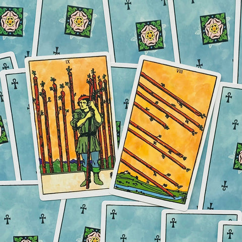 Tarot kortos Rider–Waite stiliaus — dvi kortos (IX ir VIII lazdelių) išdėstytos ant mėlyno nugarėlių fono
