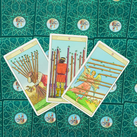 Tarot kortos trys Lazdų kortos (8, 9, 10) išrikiuotos fanu ant žalsvos ornamentuotos kortų nugarėlės, rodantis šio varianto dizainą