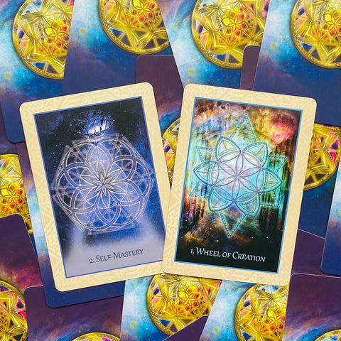 Orakulo kortos dviejų kortų išdėstymas: atvertos 'Self‑Mastery' mėlynos mandalos ir 'Wheel of Creation' spalvoto auksinio ornamentu, fonas iš užrištų kortų