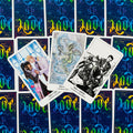 Tarot kortos su ryškiai mėlynomis nugarėlėmis, trys atverstos iliustruotos kortos (Two of Cups, Ace of Cups, King of Wands) išdėstytos fane virš uždengtų kortų