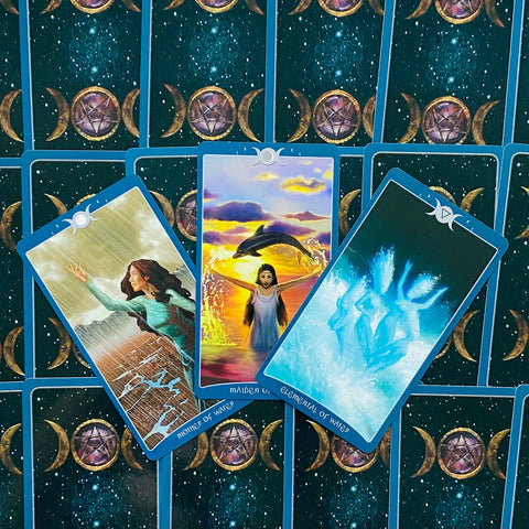 tarot kortos su mėlynais nugarėliais, trys atverstos vandens kortos centre (Motina, Mergelė, Elementalas) ant žvaigždėto mėnulio fono