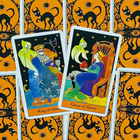 Tarot kortos Ghosts komplektas, atverstos Karalius ir Karalienė, dėmesys į spalvingas iliustracijas ir oranžines juodas nugarėles