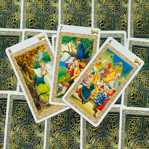 tarot kortos su celtų raštais, trys atvertos kortos centre su spalvingomis liaudies scenomis ir ugnies šokiu
