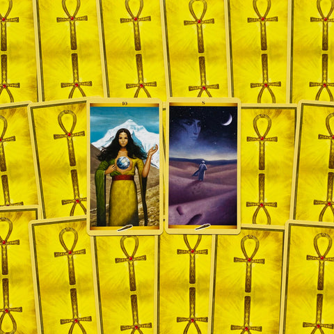 tarot kortos su geltona nugarėle, centre atverstos 10 (motina su Žeme) ir 8 (figūra dykumoje) kortos